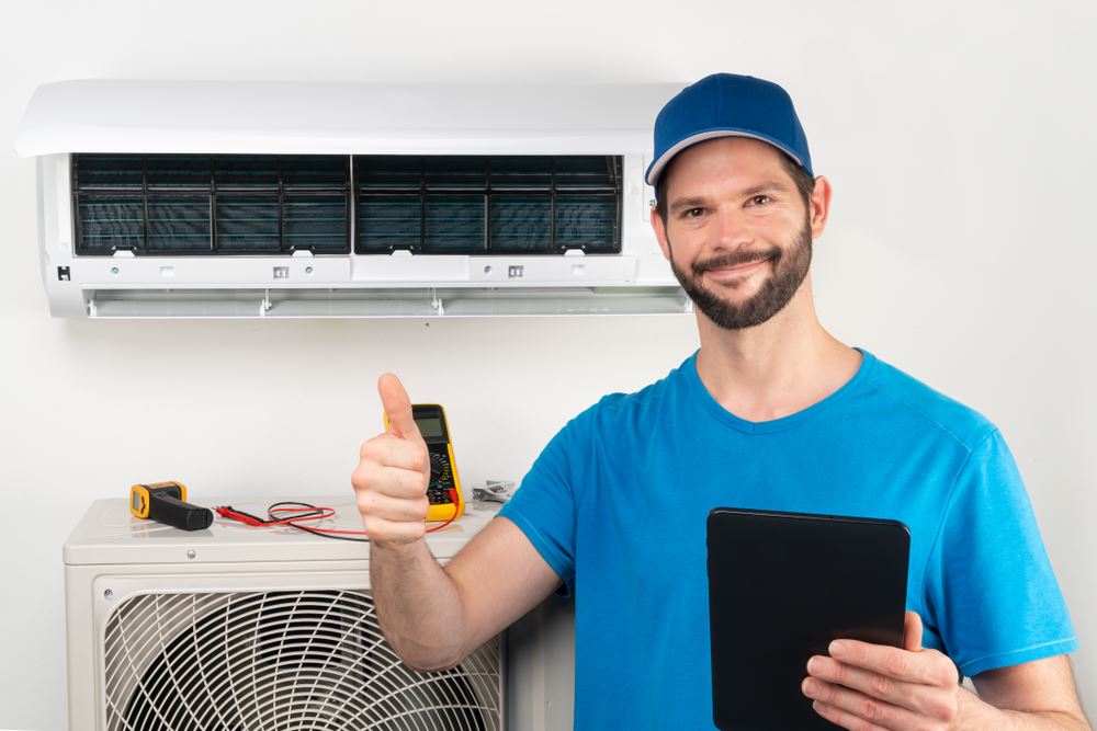 AC tech giving a thumbs up in front of AC unit